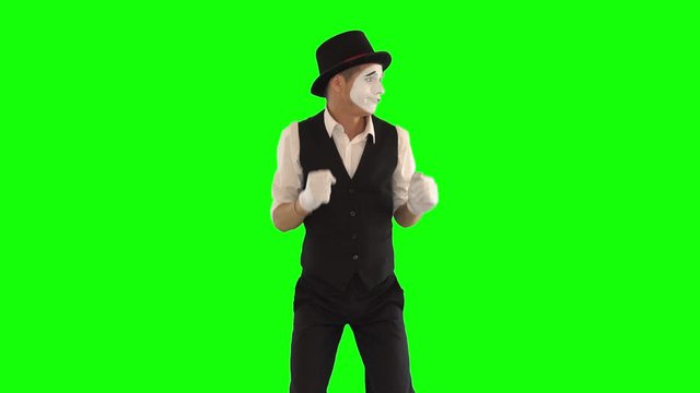 Funny male mime in white and black clothes imitating dancing. One actor performing show on green background. Chromakey