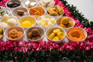 Fototapeta na wymiar Flower Rangoli with sweets/mithai and diya in bowls for Diwali or any other festivals in India, selective focus