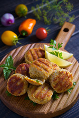 Fish cakes with lemon and herbs. Fish patties on wooden board
