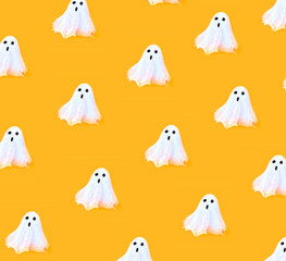 Halloween seamless white spooky ghosts on orange backgrounds. Minimal concept scary autumn.