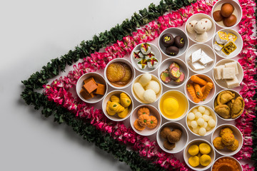 Obraz na płótnie Canvas Flower Rangoli with sweets/mithai and diya in bowls for Diwali or any other festivals in India, selective focus