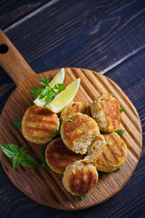 Fish cakes with lemon and herbs. Fish patties on wooden board. Overhead, vertical image