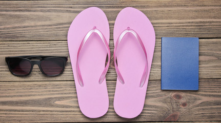 The concept of vacation on the beach, tourism. Summer traveler background. Flip flops, passport, sunglasses on wooden background. Top view. Flat lay