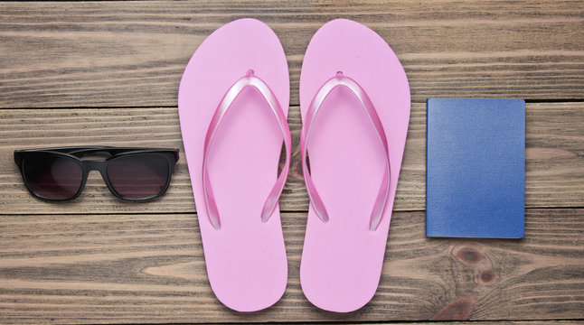 The concept of vacation on the beach, tourism. Summer traveler background. Flip flops, passport, sunglasses on wooden background. Top view. Flat lay