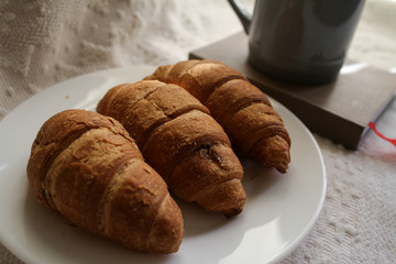 .breakfast with coffee and croissants, on a light background with a notebook