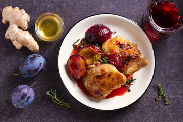Chicken thighs and plums in ginger, honey and red wine sauce with thyme. Dish ingredients on the...