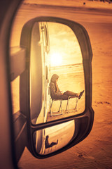 Frau beim Lesen am Strand in einem Rückspiegel gesehen