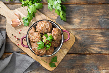 Meat cutlets in a deep dish on a wooden table