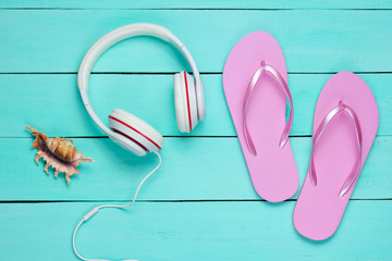 Flip flop and headphones on blue wooden background.  Summertime relax. Summer vacation. Beauty and fashion. Top view. Flat lay