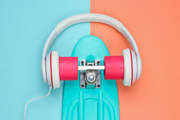 Hipster outfit. Skateboard with headphones on colored background. Creative fashion minimalism. Trendy old fashionable style. Minimal summer fun. Music concept. Top view