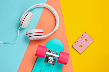 Hipster outfit. Skateboard with headphones, audio cassette on purple background. Creative fashion minimalism. Trendy retro 80s style. Minimal summer fun. Music concept. Top view