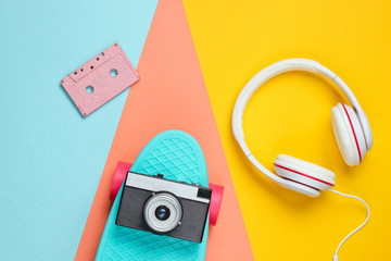 Hipster outfit. Skateboard with headphones, audio cassette on colored background. Creative fashion minimalism. Trendy retro 80s style. Minimal summer fun. Music concept. Top view