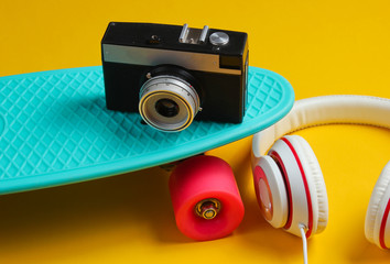 Hipster outfit. Skateboard with headphones on yellow background. Creative fashion minimalism. Trendy retro 80s style. Minimal summer fun © splitov27
