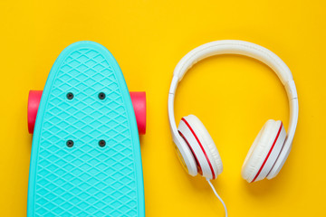 Hipster outfit. Skateboard with headphones on yellow background. Creative fashion minimalism. Trendy old fashionable style. Minimal summer fun. Music concept
