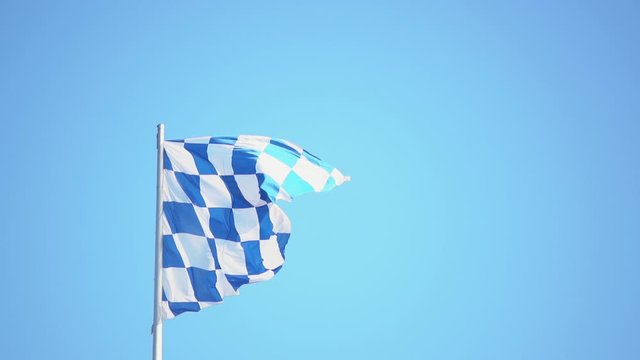 Slow motion bavarian flag on bavarian blue and white poll in the wind blue sky background. Bavaria is home of the famous oktoberfest