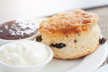 Homemade fresh baked scone with cream and straberry jam on rattan mat.