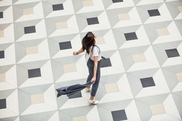 Young adult beautiful brunette girl happy on tile with geometric pattern top view
