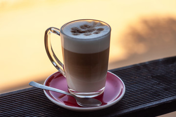 Frothed cappuccino with spoon on a railing