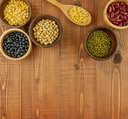 Flat lay,top view assorted beans including red bean,soybeans,black beans,mung beans on brown,beige wooden background with copy space