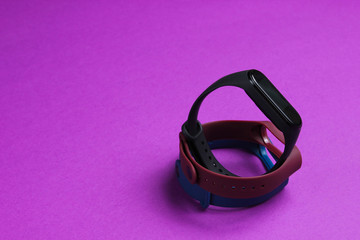 Smart watch with interchangeable bracelets on purple background. Fitness tracker. Modern gadgets