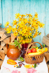 Bouquet of flowers and basket with autumn crop of seasonal vegetables