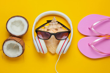 Creative summer beach background. Beach holidays. Headphones, sunglasses, coconut, shell, flip flop...