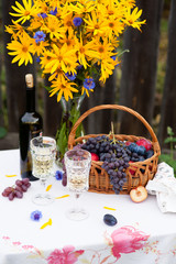 bouquet of flowers, wine, glasses and grapes against the background of an old fence