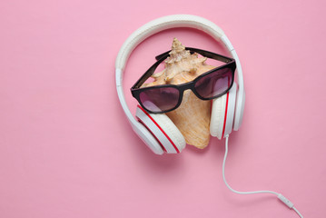 Creative summer minimalism. The face of the shell, sunglasses, headphones on pink pastel background. Top view