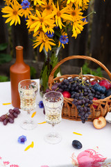 bouquet of flowers, wine, glasses and grapes against the background of an old fence