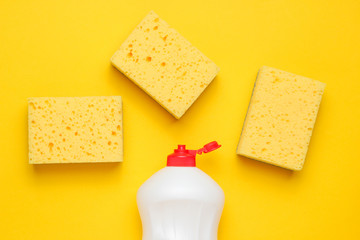 Set of housewives for washing dishes. Dishwasher. Bottle of washing utensils, sponges on yellow background. Top view.