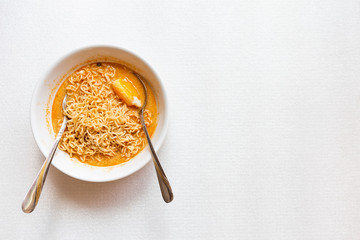 Spicy  Tomyum instant noodle soup with egg on white texture background, unhealthy food