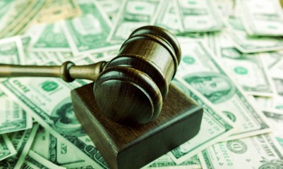 Wooden gavel on banknotes on table, on  background