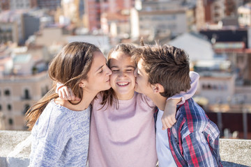 Dos hermanos besando a la vez a su hermana pequeña en la azotea