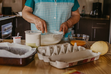adult woman in the kitchen kneading the mix for sweets and desserts