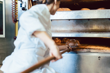 Baker putting bread in the bakery oven