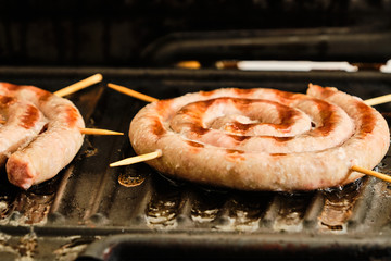 Cooking white spiral sausages on grill