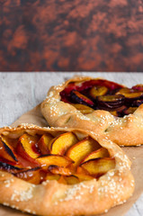 Homemade galettes with peaches and plums with sesame. Sweet fruit pies. Vegetarian dessert. Closeup. Selective focus