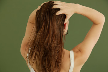 Studio shot of woman applying hair oil with her fingers - obrazy, fototapety, plakaty