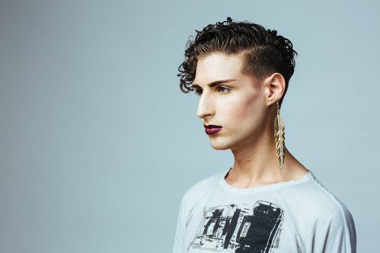Profile portrait of a young  man with make up and earring