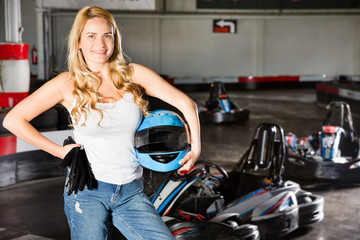 Fototapeta na wymiar Female racer holding helmet on kart track