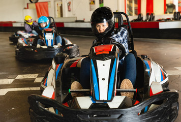 Female racer in helmet driving kart on track - obrazy, fototapety, plakaty