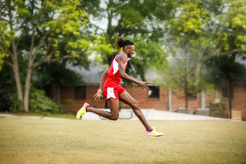 Young Handsome African American Black Male outside running in the field of a small town in georgia city ampitheater. track and field star