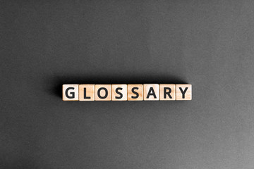Glossary - word from wooden blocks with letters, alphabetical list with words meanings dictionary glossary  concept, top view on grey background - obrazy, fototapety, plakaty