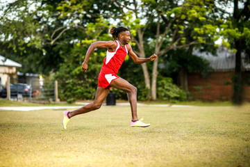 Naklejka premium Young Handsome African American Black Male outside running in the field of a small town in georgia city ampitheater. track and field star