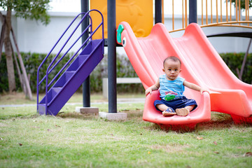 Nonthaburi, Thailand, Aug 28, 2019 - Little baby boy sitting on slider in public park