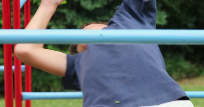 Young boy playing in monkey bars outside