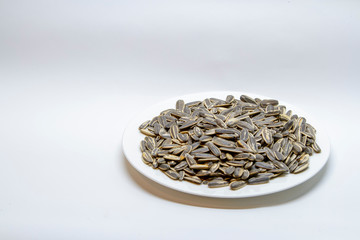 Dried sunflower seeds in the white plate on white background.