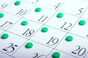 calendar sheet at an angle on which the tablets are on each date