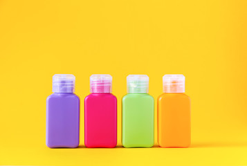 Colorful plastic travel bottles for skincare products or different purposes on yellow background