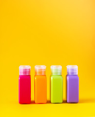 Colorful plastic bottles for skincare products or different purposes on yellow background